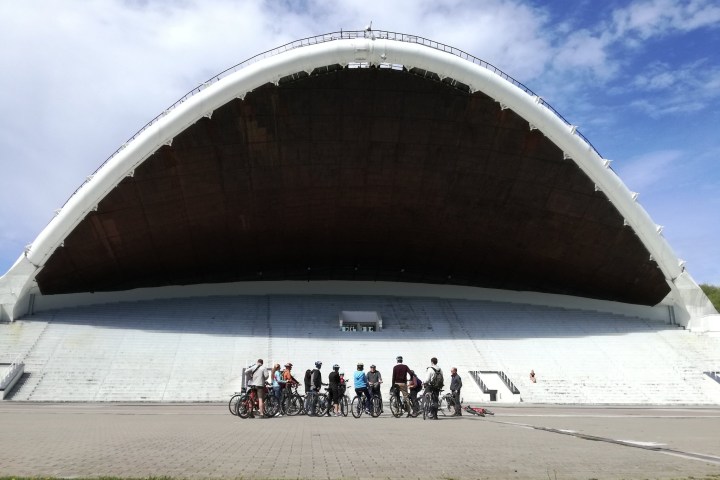 A group of people with bicycles posing near a dome