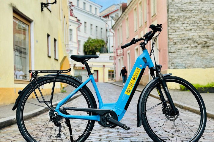 Blue bicycle parked on cobblestone street, historic buildings in background.
