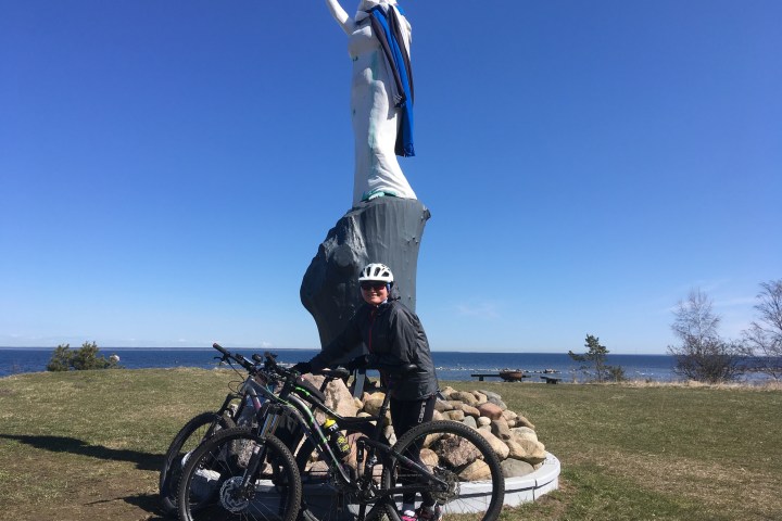 a man riding a bicycle on a dirt field parking next to a statue