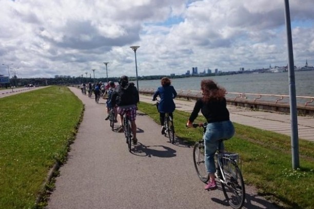 a person riding a bicycle on the side of a road in Tallinn