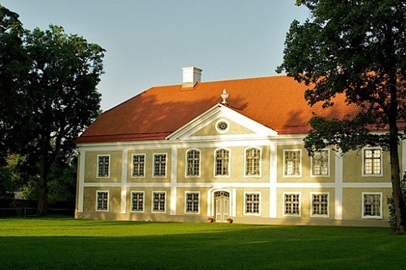 a large brick building with a clock on top of a lush green field