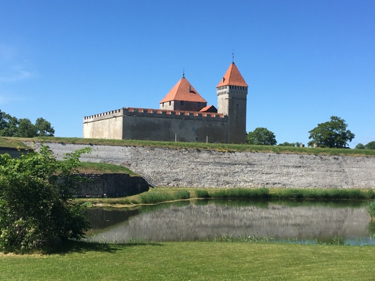 a castle on top of a grass covered field with Saaremaa in the background